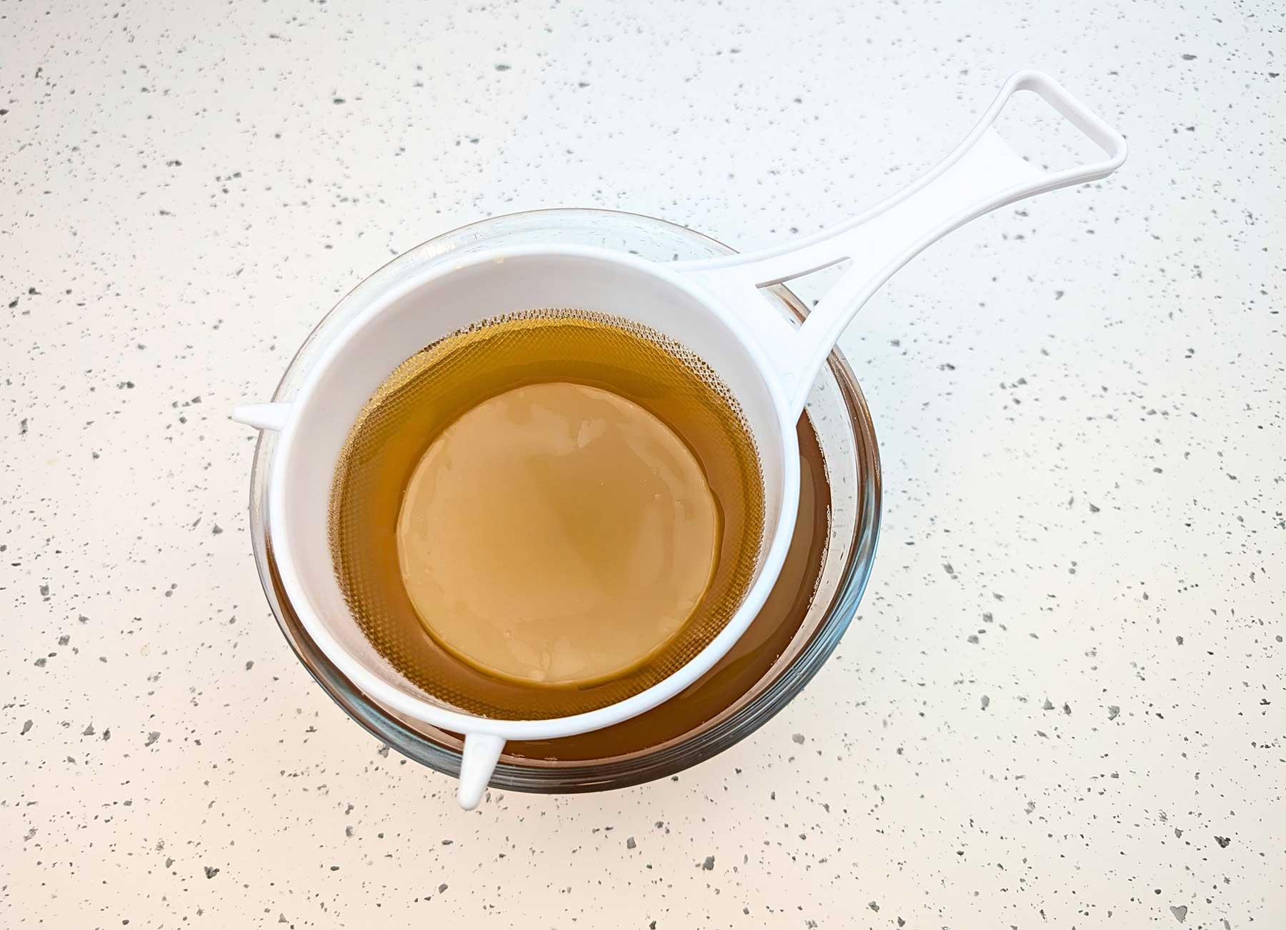 SCOBY de kombucha y líquido iniciador filtrados después de la fermentación primaria, listos para reutilizar en un nuevo lote de kombucha casera.